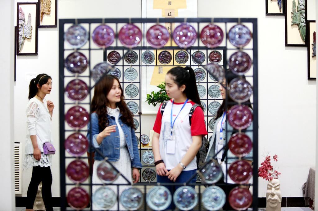 郑转兄(左二)正在向参观者介绍她的创意作品《归》